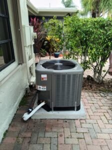 HVAC replacement in Pompano Beach showing a heat pump installed on a brick patio in front of a house, with a clear and sunny exterior