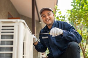A man in a blue uniform performing AC repair in Margate, FL, holding a tool while servicing an air conditioner
