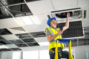 Ceiling fan installation in progress by one of the skilled HVAC contractors in Sunrise FL, working safely on a ladder in a bright interior space