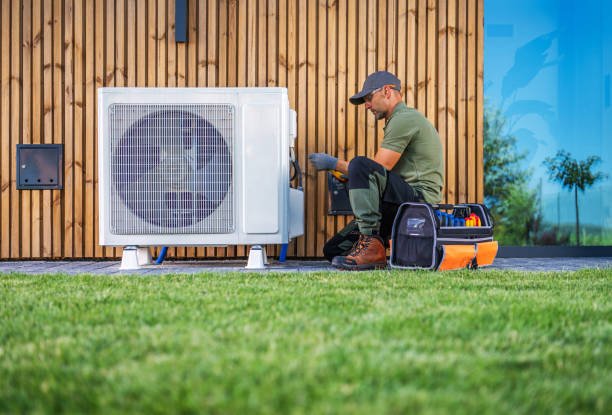 The Best AC Repair Service Near Me in Coconut Creek, FL A man repairs an air conditioner, focused on the unit with tools in hand, in a well-lit indoor environment – AC repair service near me in Coconut Creek, FL.