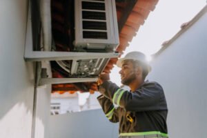 AC not turning on – technician in safety gear repairing a rooftop air conditioner unit.