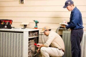 Two technicians working on a 2-ton AC unit in a residential setting, highlighting professional installation and home cooling efficiency.
