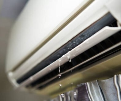 Close-up of a window air conditioner leaking water, showing signs of a clogged drain or internal AC issue.