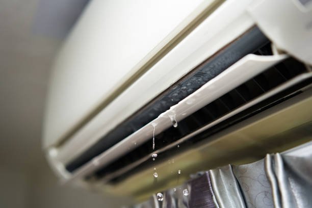 Close-up of a window air conditioner leaking water, showing signs of a clogged drain or internal AC issue.