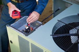 A technician performs AC maintenance in Pompano Beach, carefully servicing an indoor air conditioning unit with tools in hand.