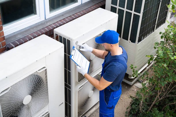 A man in blue overalls inspects a heat pump during routine AC maintenance in Pompano Beach, ensuring it operates efficiently.