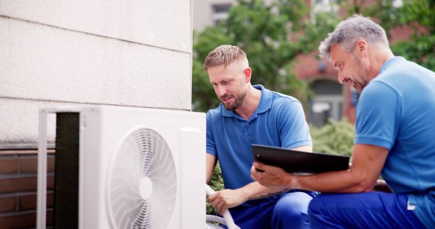 Two HVAC technicians in blue shirts performing Carrier 3-ton AC unit installation at a residential property.