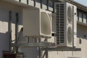 Air conditioning units mounted on a building, with the sound of AC compressors humming in the background. 