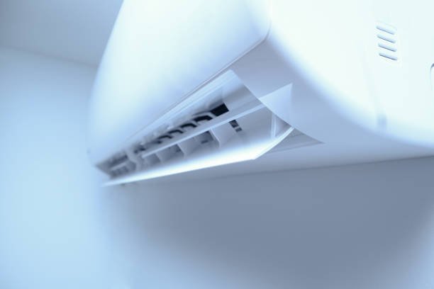 Wall AC unit in a bright white room, enhanced by a soft blue glow.