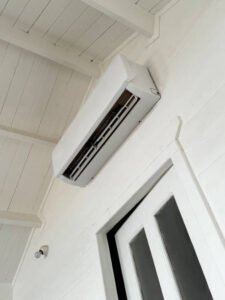 A white ductless mini-split air conditioner mounted on the side of a house, providing efficient cooling.
