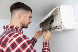A man performs maintenance on an air conditioner, ensuring it operates efficiently.