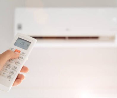 Individual with a remote control, standing before an air conditioner that shows a warning: "AC Not Cooling."