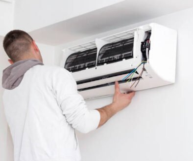 A man is working on an air conditioner in a clean, white room, demonstrating air conditioner repair skills.
