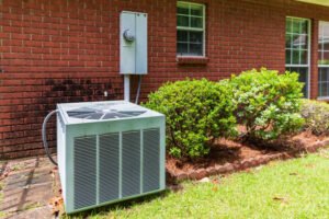 Close-up image of a heat pump surrounded by garden plants, illustrating its function in AC condenser replacement.