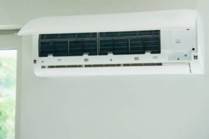 A white air conditioner mounted on the wall, part of a residential HVAC service setup.