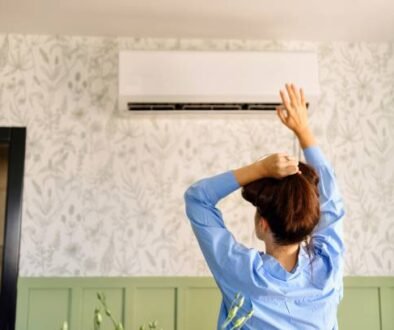 Woman in a blue shirt stands in front of an AC blowing warm air.