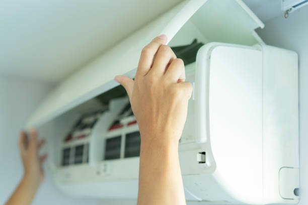 An individual fixing an air conditioner, showcasing the services of an AC repair company.