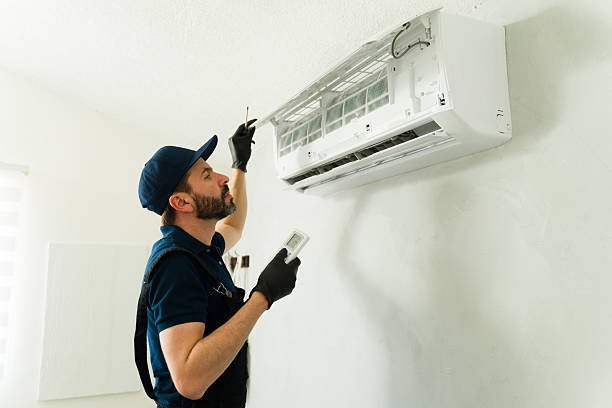 A man in blue gloves works on an air conditioner, providing essential Air Conditionere repair services.