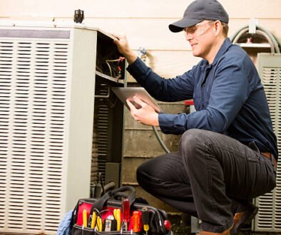 A man kneeling next to an air conditioner, representing professional HVAC installation services.