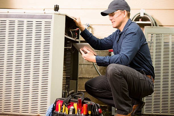A man kneeling next to an air conditioner, representing professional HVAC installation services.