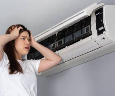 A woman examines her air conditioner, consideringWarning Signs to Replace Your Air Conditioner.