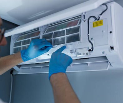 A man wearing blue gloves is repairing an air conditioner, demonstrating AC repair services.