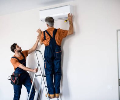 Two men installing a wall-mounted air conditioner, focused on the unit and tools in a residential setting.
