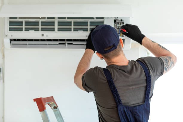 A man is repairing an air conditioner, focused on fixing the unit in a residential setting.