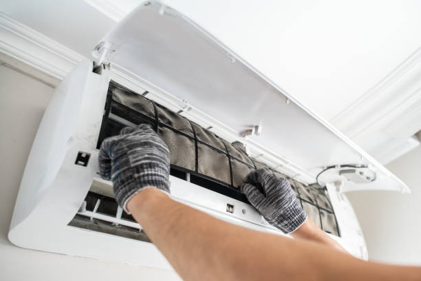 A technician is working on an air conditioner, adjusting components to ensure proper functionality.