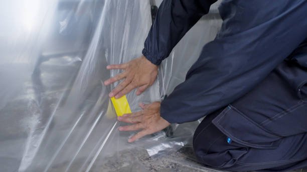 A man in a blue jacket inspects a piece of plastic during an air conditioning installation process.