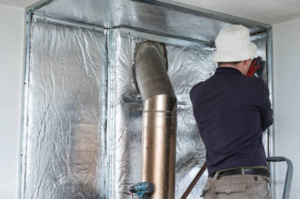 How Can HVAC Service Improve Efficiency and Reduce Bills? 1 A man in a hard hat and safety vest works on an HVAC pipe, ensuring proper installation and maintenance.
