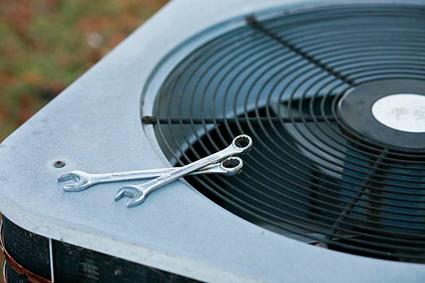 An HVAC technician repairs an air conditioning unit, demonstrating expertise in AC repair services.