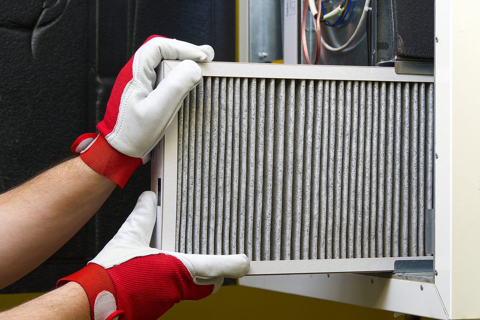 An individual in gloves is holding an HVAC filter, indicating a focus on air quality and system upkeep.