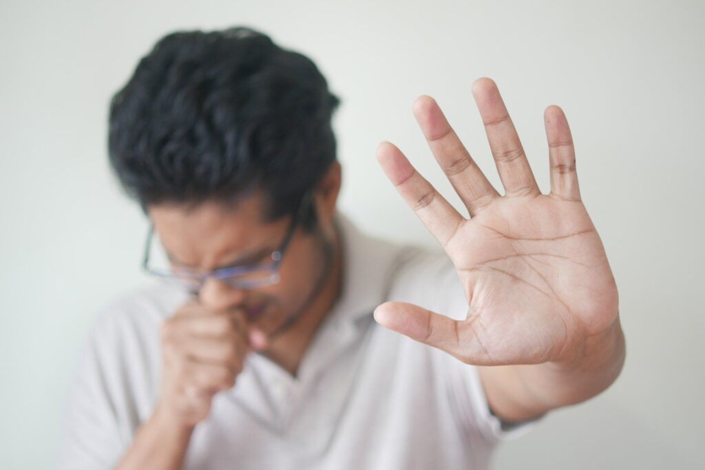 A man wearing glasses and a white shirt holds up his hand, likely in a presentation about HVAC filters.