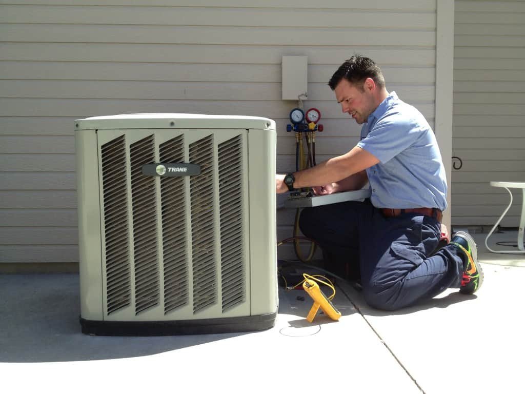 A man is replacing an HVAC unit, focused on the installation process in a residential setting.