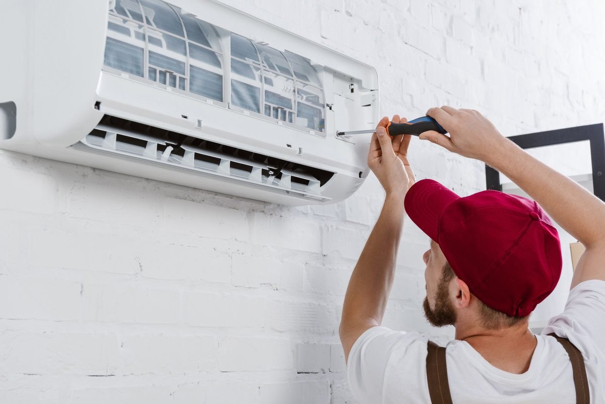 A man working on residential AC repair, focused on fixing the unit in a home setting.